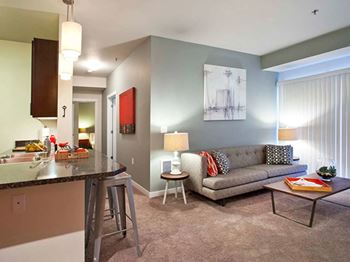 A living room with a couch and a kitchen with a breakfast bar 