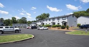 Lawrenceville apartment for rent - A parking lot with cars and a building in the background at The Madison Apartments and Townhomes, Lawrenceville, GA