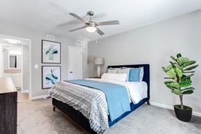 Marietta apartment for rent - A bedroom with a bed, a ceiling fan, and a plant at Barcelo at East Cobb Apartments, GA, 30067