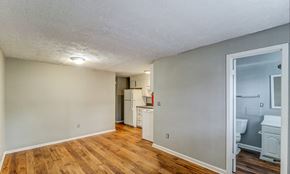Norcross apartment for rent - A room with wooden floors and a white ceiling with a kitchen area visible through the door.at Waverly Manor Townhomes, Norcross, 30071