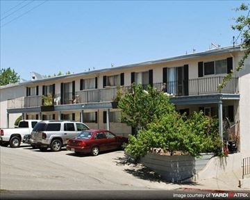 Novato apartment for rent - A red car is parked in front of a building with a balcony.