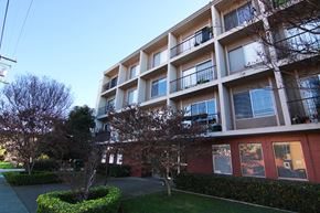 Alameda apartment for rent - A large apartment building with balconies and trees in front.