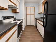 Kansas City townhouse for rent - A kitchen with a black refrigerator, white cabinets, and a wooden floor.