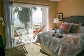 Alameda apartment for rent - A bedroom with a large bed and a view of the beach through the sliding glass door.