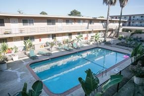 Alameda apartment for rent - A swimming pool surrounded by chairs and plants in front of apartment buildings.