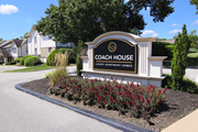 Kansas City townhouse for rent - A sign for Coach House Luxury Apartment Homes is surrounded by plants.