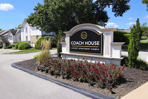 Kansas City townhouse for rent - A sign for Coach House Luxury Apartment Homes is surrounded by plants.