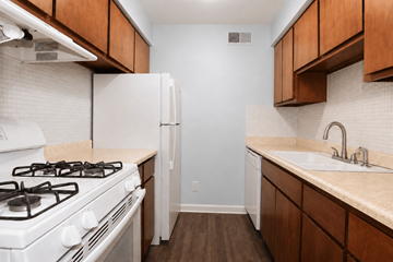 Olathe apartment for rent - A kitchen with a white gas stove and wooden cabinets.