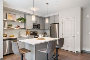 Brockton apartment for rent - A modern kitchen with a white island and grey chairs.