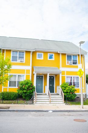 Roxbury apartment for rent - a yellow house with green bushes in front of it