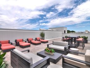 Dorchester apartment for rent - A patio with red and grey furniture and a white building in the background.