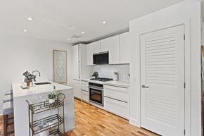 Washington apartment for rent - A kitchen with white cabinets and a white island with a sink.