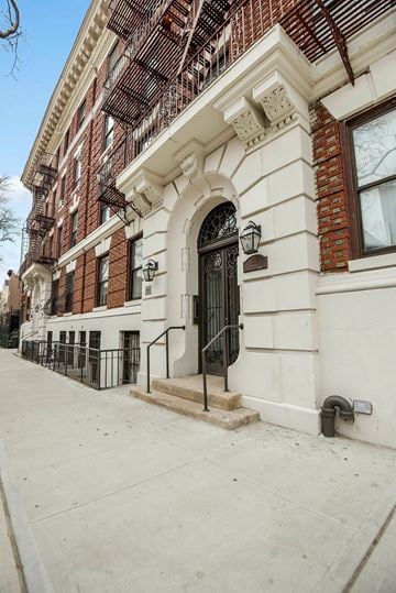 Brooklyn apartment for rent - A white building with a black door and a metal railing.