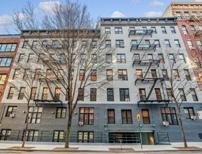 Manhattan apartment for rent - A grey building with a tree in front of it.