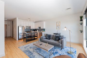 Boston apartment for rent - a living room with a couch and a coffee table and a kitchen in the background