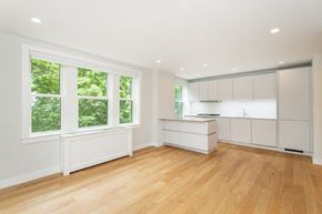 Somerville apartment for rent - an empty kitchen with white cabinets and a large window