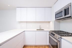 Boston apartment for rent - a kitchen with white cabinets and a stove and a microwave