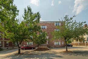 Somerville apartment for rent - A red car is parked on the street in front of a brick building.