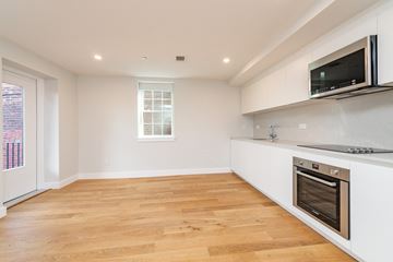 Boston apartment for rent - a white kitchen with a wooden floor and a stove and a television