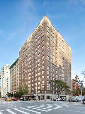 Manhattan apartment for rent - A large brown building is in the middle of a city street.