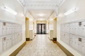 Manhattan apartment for rent - A hallway with white lockers on both sides and a black door at the end.