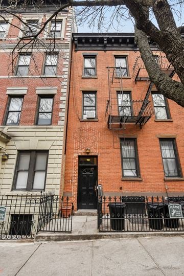 Brooklyn apartment for rent - A red brick building with a black door and windows.