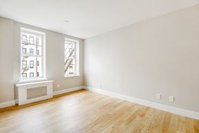 Brooklyn apartment for rent - A room with wooden floors and a window showing a building outside.