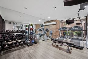 Philadelphia apartment for rent - A gym with a variety of equipment including dumbbells, weight plates, and a bench press.