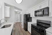 Philadelphia apartment for rent - A black refrigerator and oven in a kitchen with white cabinets.