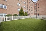 Landsdale apartment for rent - A white picket fence surrounds a green lawn in front of a brick building.