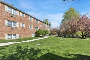 Warrington apartment for rent - A grassy area in front of a brick building with trees.