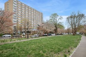 Philadelphia apartment for rent - A grassy area in front of a tall building with a street sign.