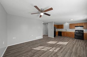 Lees Summit apartment for rent - A spacious room with a ceiling fan and wooden flooring.