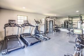 Kansas City apartment for rent - a gym with cardio equipment and weights on the floor