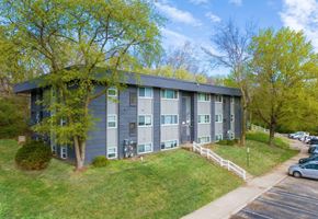 Kansas City apartment for rent - a gray building with green trees in the background