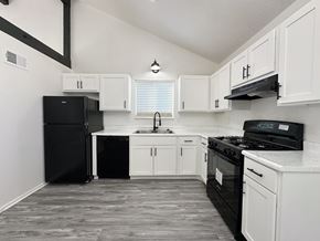 Blue Springs apartment for rent - an empty kitchen with white cabinets and black appliances