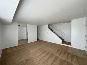 Kansas City townhouse for rent - a living room with a carpeted floor and a staircase in the background