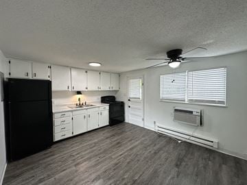 Kansas City apartment for rent - a kitchen with white cabinets and black appliances and a ceiling fan