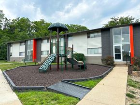 Kansas City apartment for rent - a playground with a slide and chairs in front of a building