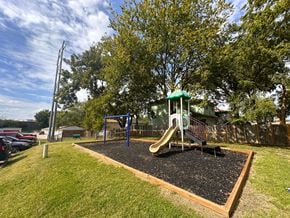 Overland Park apartment for rent - A playground with a green slide and a brown swing set.