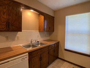 Overland Park apartment for rent - A kitchen with wooden cabinets and a white dishwasher.
