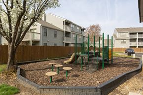 Overland Park apartment for rent - A playground with a green swing set and a tree in the background.