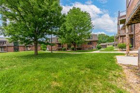 Lee's Summit apartment for rent - a grassy area with trees and buildings in the background