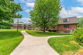 Lee's Summit apartment for rent - a grassy area with trees and buildings in the background