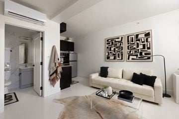 Kansas City apartment for rent - A modern living room with a white couch and a large abstract painting on the wall.