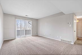 Kansas City apartment for rent - A spacious room with a carpeted floor and a sliding glass door.