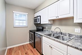 Kansas City apartment for rent - A kitchen with a black stove top oven and white cabinets.