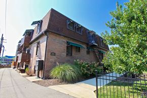 Kansas City apartment for rent - A brick building with a green awning and a black fence in front.