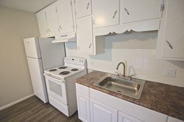 Kansas City apartment for rent - A kitchen with white cabinets and a stove top oven.
