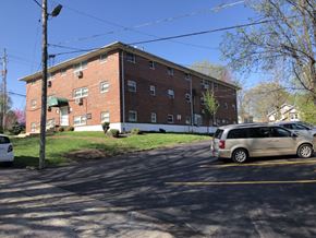 Kansas City apartment for rent - A building with a green awning and a white car parked in front.